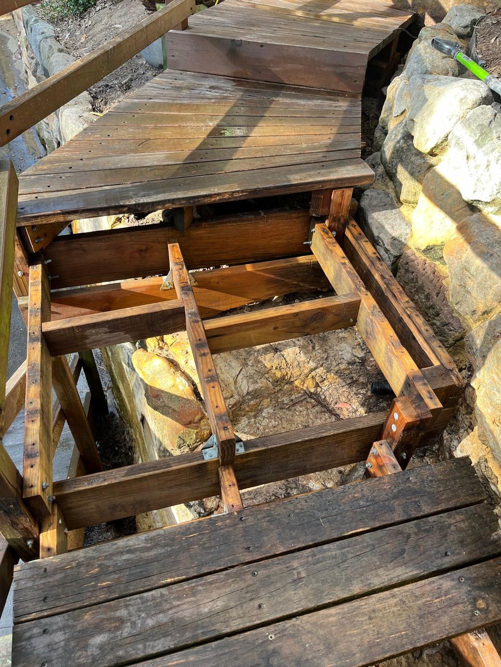 Garden stairs with the rotten treads removed, showing the timber frame and the sandstone and soil underneath
