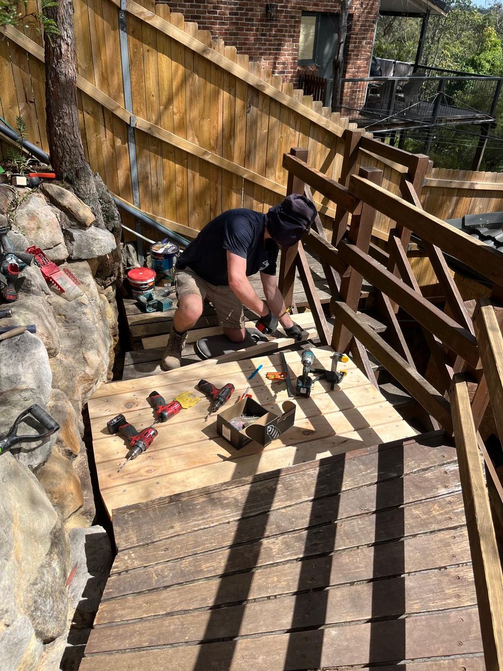 James from James of all trades on his knees fitting new treated pine treads to the garden stairs