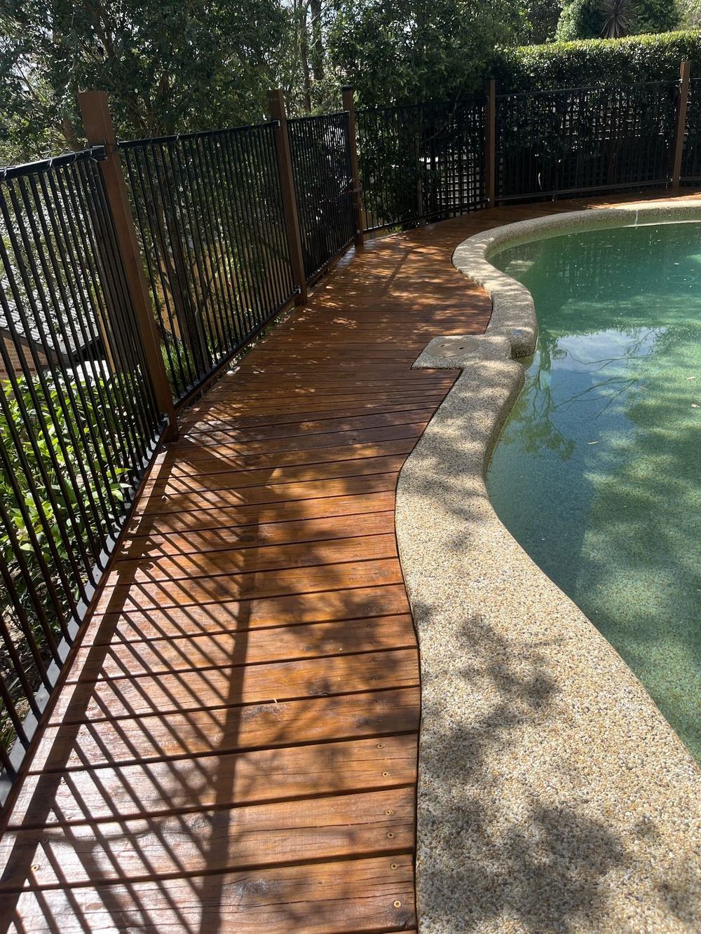 Pool deck along the fence after sanding and restaining