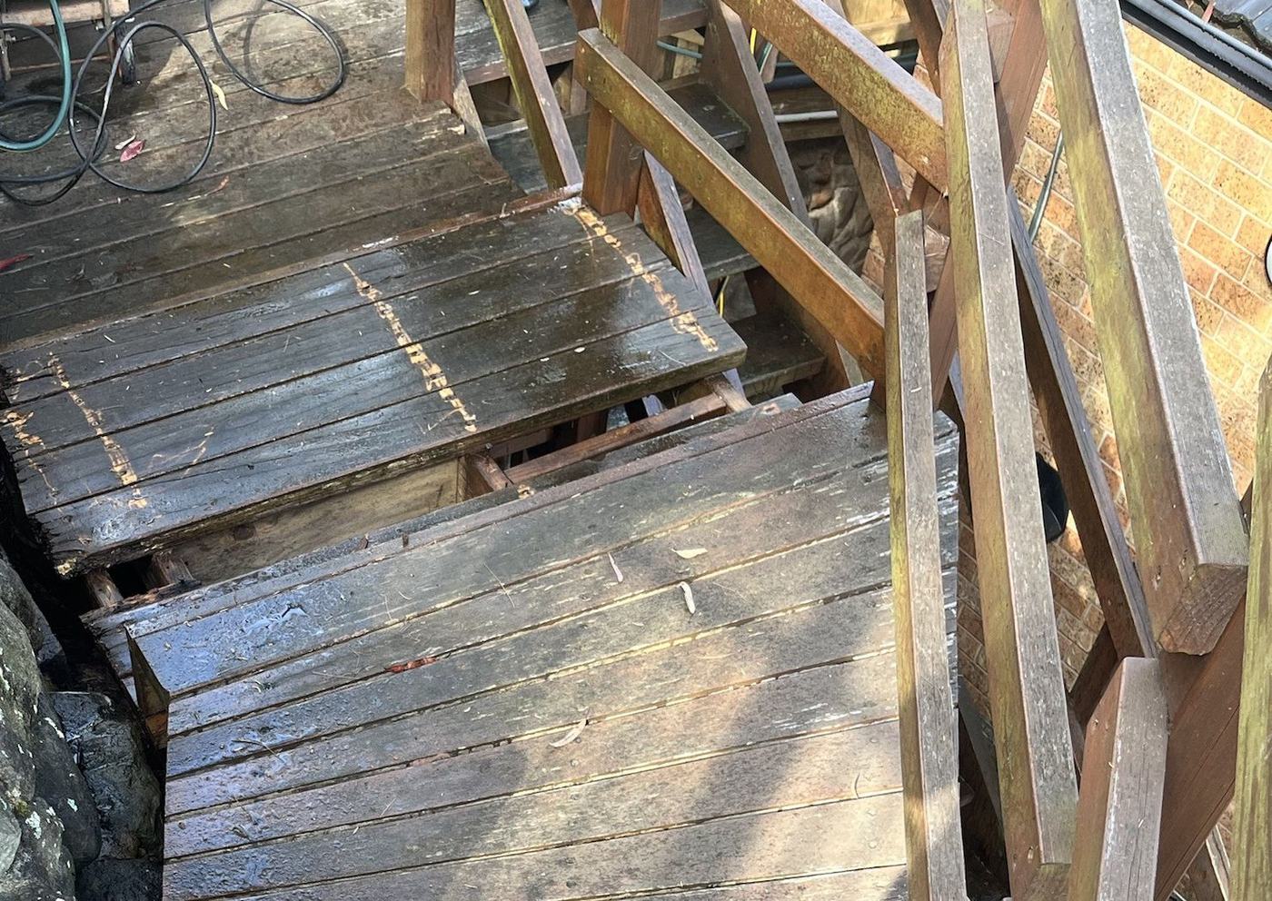 Looking down on worn, weathered stair treads with gaps where failed boards have broken away, showing the frame underneath