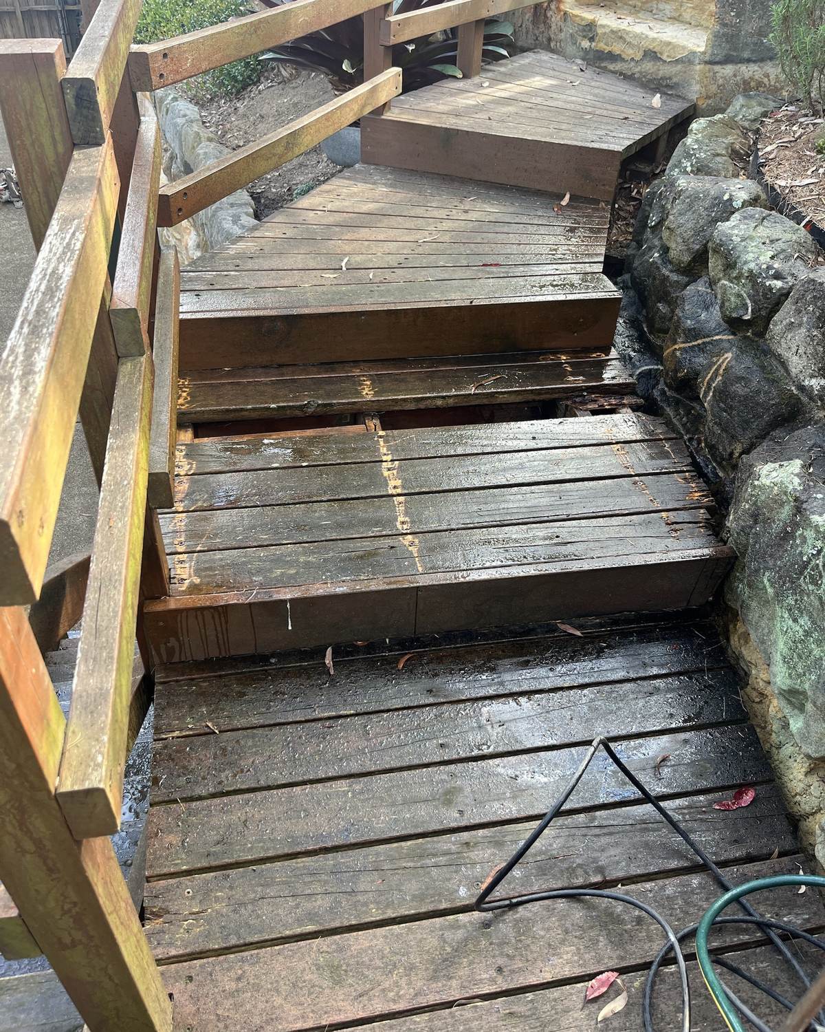 Rotten timber stair treads beside a sandstone wall